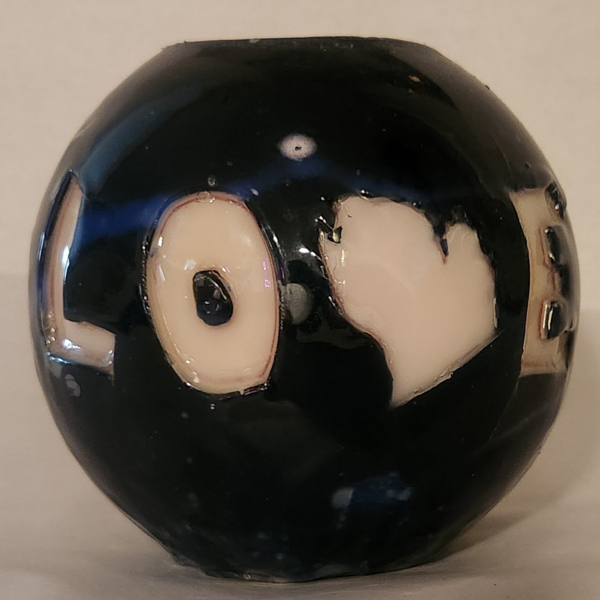 Hand carved spherical candle with black outside and "LOVE" carved in the sign with the "V" being replaced by the outline of state of Michigan featured. It is shown being lit externally.